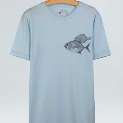 T-shirt azul clara com estampa de dois peixes cinzentos no peito esquerdo, pendurada num cabide de madeira.