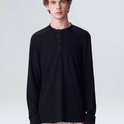 Homem com camisola preta de manga longa e calças bege