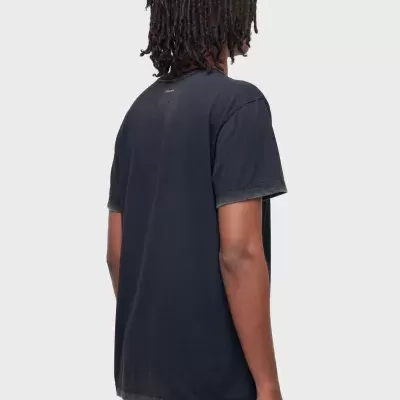 T-shirt preta vista de costas com texto pequeno no topo e calças de ganga azul.