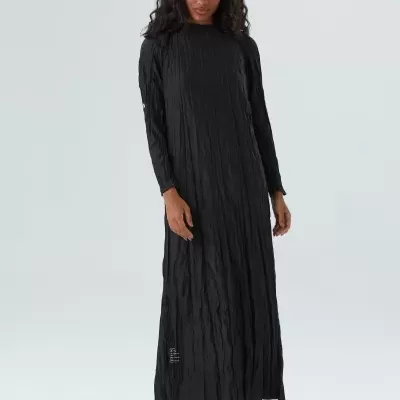Vestido comprido preto com textura franzida usado por mulher