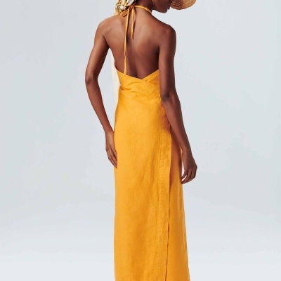 Mulher de costas com vestido amarelo comprido de alças finas e chapéu de palha