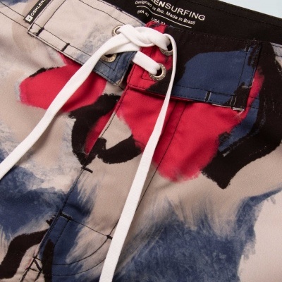 Calções de surf coloridos com cordão branco e etiqueta com texto OSKLENSURFING.