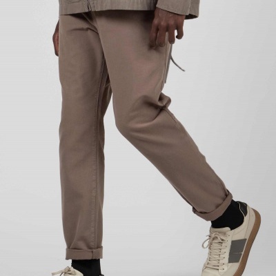 Homem a usar pantalonas castanhas e ténis bege com sola castanha