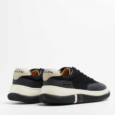 Par de sapatilhas pretas com sola espessa e pala bege com texto OKLEN