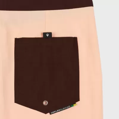 Parte de roupa rosa e castanha com bolso castanho e etiqueta preta