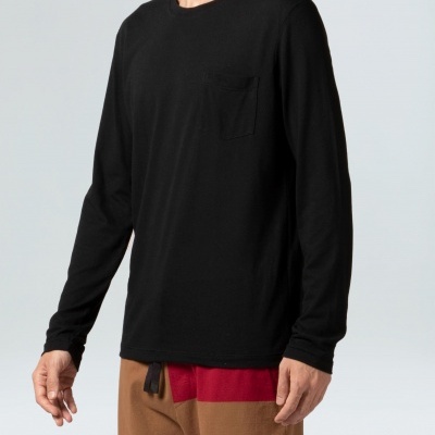 Camisola preta de manga comprida com bolso no peito e calças castanhas com detalhe vermelho.