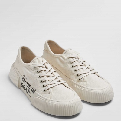 Sapatilhas brancas de lona com sola grossa e texto MADE IN BRAZIL