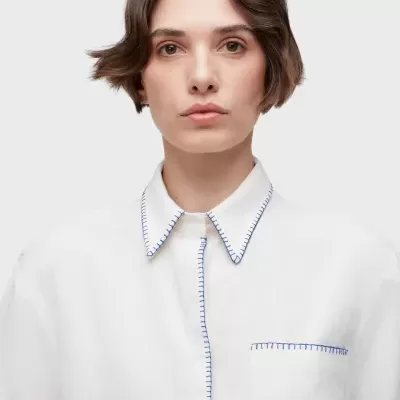 Camisa branca com costuras azuis e gola de bico