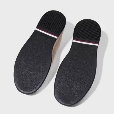 Solas de sapatos pretas com detalhe de riscas e parte superior em material trançado bege