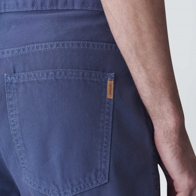 Calças azuis com bolso traseiro e rótulo castanho na lateral