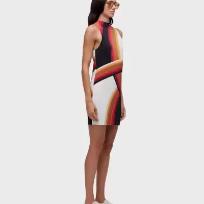 Vestido justo colorido com padrão de riscas verticais e curvas em várias cores, usado por uma mulher com óculos de sol amarelos e sapatilhas brancas.