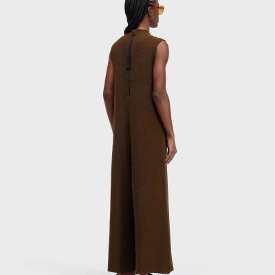 Pessoa de costas com jumpsuit castanho, chinelos brancos e óculos amarelos