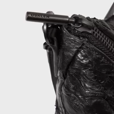 Fecho de correr preto em carteira ou bolsa de couro preto enrugado com puxador metálico OSKLEN