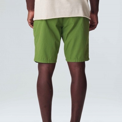 Pessoa vista de costas a usar calções verdes, t-shirt bege e ténis brancos com sola preta.