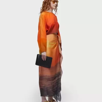 Mulher com vestido longo colorido e sandálias douradas