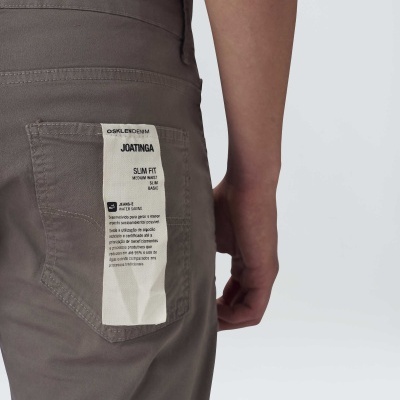 Calças cinzentas slim fit com etiqueta branca na parte traseira e mão ao lado