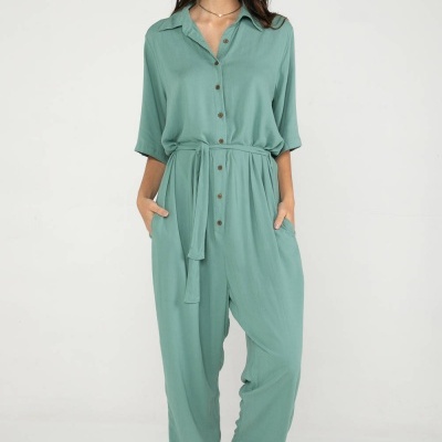 Macacão verde-água com botões e cinto, usado por mulher com sandálias bege