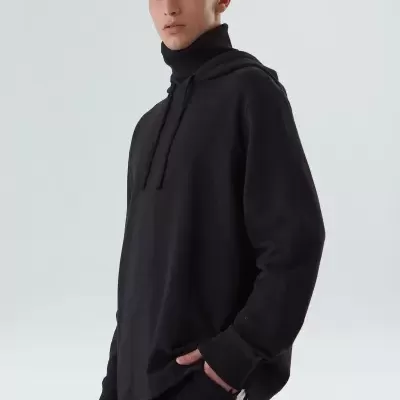 Homem com camisola preta de gola alta e calças pretas com riscas brancas