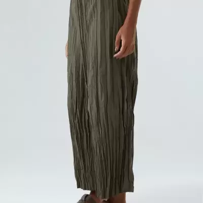 Calças plissadas verde-oliva femininas com sandálias castanhas em fundo branco