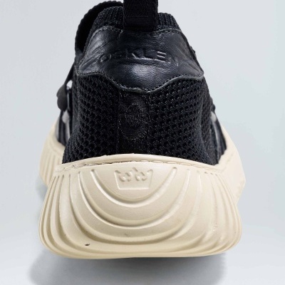 Sapatilha desportiva preta com sola creme e detalhes em relevo vista de trás