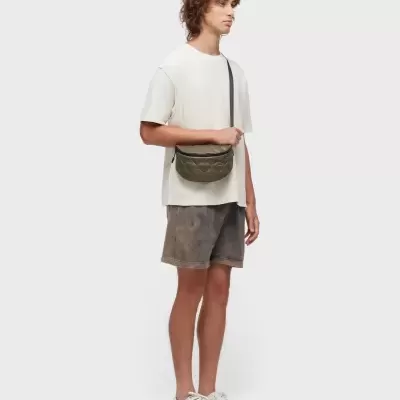 Homem com roupa casual e mala tiracolo em fundo branco