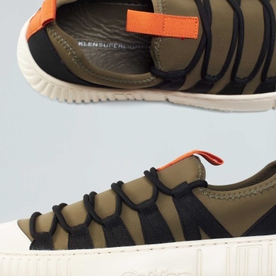 Ténis desportivos verdes e pretos com sola branca e detalhes laranja