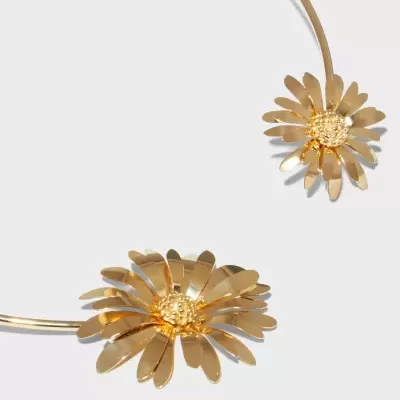 Colar dourado com flores metálicas sobre fundo cinza