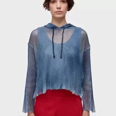 Camisola azul de rede com capuz e cordões pretos sobre top azul com calças vermelhas