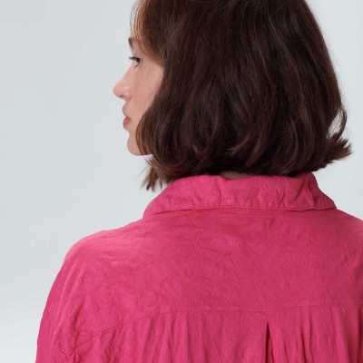 Pessoa vista de costas com camisa rosa e cabelo castanho curto