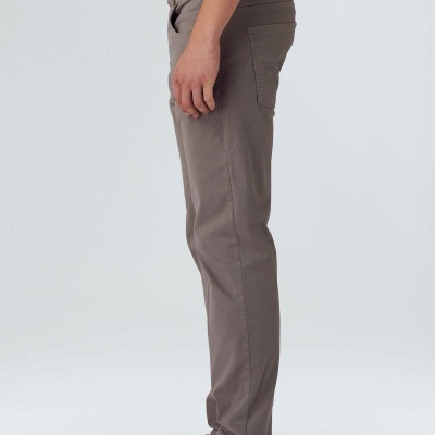 Calças castanhas, ténis bege, t-shirt verde, fundo claro