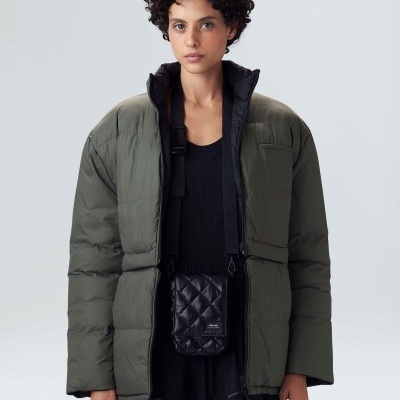 Pessoa a usar casaco acolchoado verde-oliva com bolsa preta pendurada no pescoço