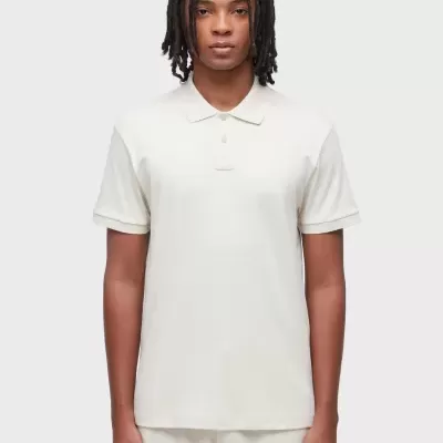 Polo branco com colarinho clássico e botões usado por modelo com calças claras