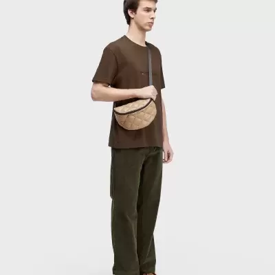 Modelo com t-shirt castanha e mala bege matelassê
