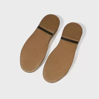 Solado de sapatos castanho claro com bandas pretas no calcanhar sobre fundo cinza