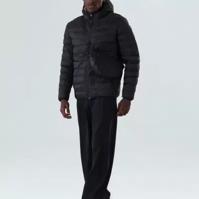 Homem a usar casaco acolchoado preto e bolsa transversal preta em fundo claro