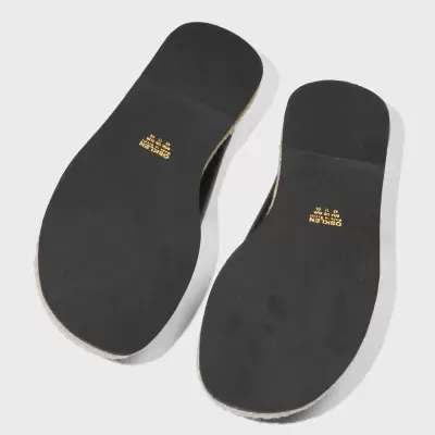 Solas pretas de chinelos com texto dourado sobre fundo cinza claro.