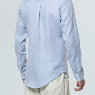 Camisa azul clara de manga comprida vista de costas, combinada com calças bege.