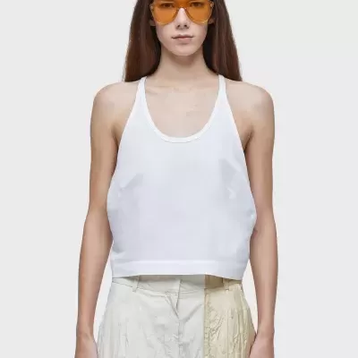 mulher com top branco, saia bege e óculos de sol com lentes amarelas