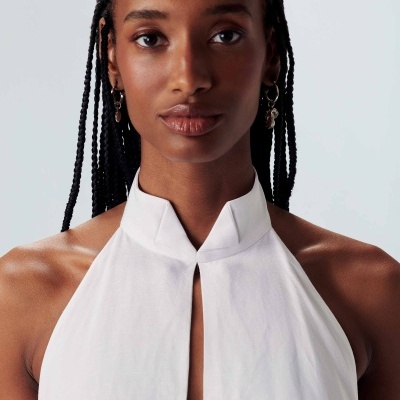 Mulher com vestido branco gola alta e corte vertical frontal