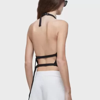 Mulher de costas com top preto de tiras e calções brancos canelados