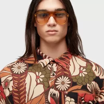 Homem com camisa floral castanha e óculos de sol castanhos
