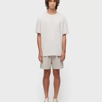 Homem com t-shirt bege e calções bege curtos com sapatilhas bege de detalhes pretos