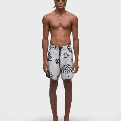 Homem com calções de banho brancos com padrões pretos e óculos de sol amarelos