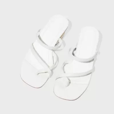 Sandálias brancas minimalistas com tiras finas em fundo cinza claro