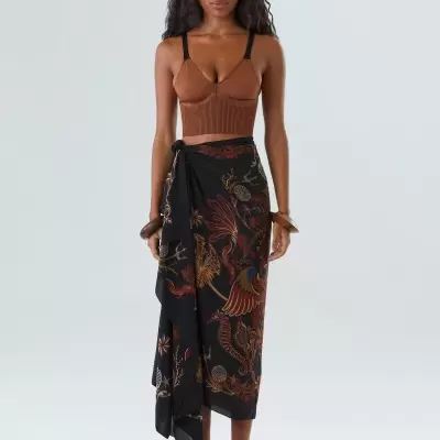 Top cropped castanho com alças pretas e saia preta estampada comprida, usada por modelo em fundo neutro.