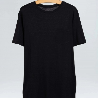 T-shirt preta de manga curta com bolso pendurada em cabide de madeira.