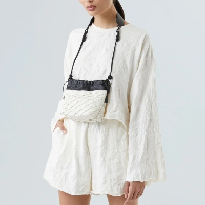 Mulher com conjunto branco e bolsa pequena tiracolo preta e branca