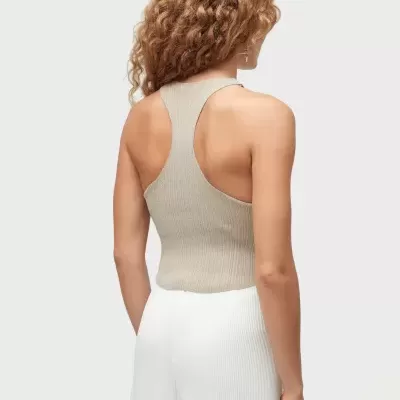 Blusa de alças bege com decote nadador nas costas e saia branca plissada