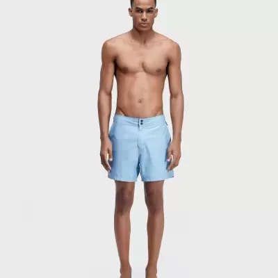 Homem a usar calções de banho azuis claros com dois botões.