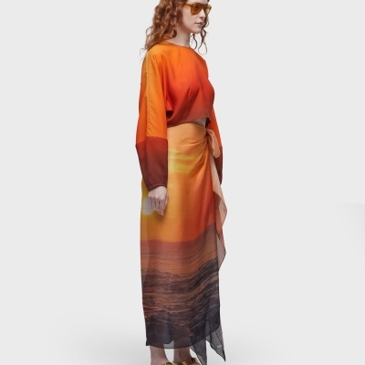 Mulher vestindo vestido longo degradê laranja e sandálias douradas